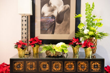 Poinsettias in front of a painting as part of the Holiday Sparkle package.